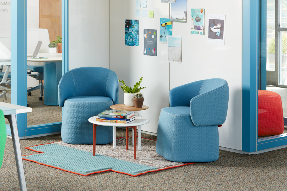 Two blue arm chairs in front of a glass wall and a whiteboard wall